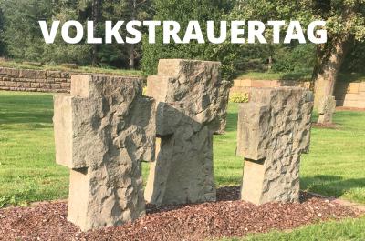 Ein Foto dreier steinerner Kreuze auf dem Friedhof in Donsbrüggen, darüber das Wort "Volkstrauertag"