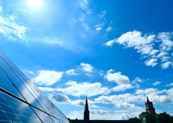 Ein Bild von Solarmodulen auf dem Rathausdach, im Hintergrund die Schwanenburg