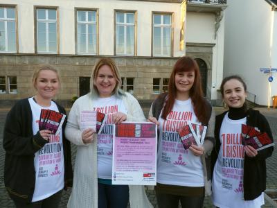 Vie junge Frauen halten Plakate und Karten für die Aktion 1 Billion Rising hoch