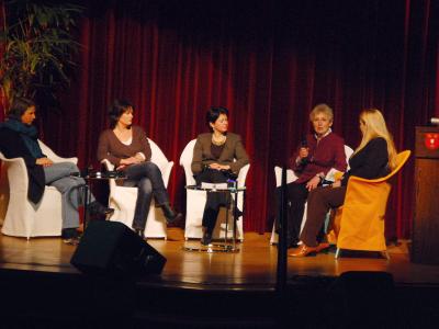 Eine Gruppe von Frauen sitzt in einem Halbkreis auf einer Bühne 