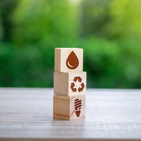 Gestapelte Holzwürfel mit Symbolen der Nachhaltigkeit