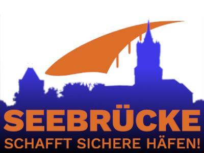 Logo der Aktion Seebrücke schaft sichere Häfen vor einem Schattenbild der Schwanenburg
