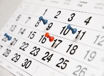 Kalenderblatt mit drei blauen und einem roten Reißnagel