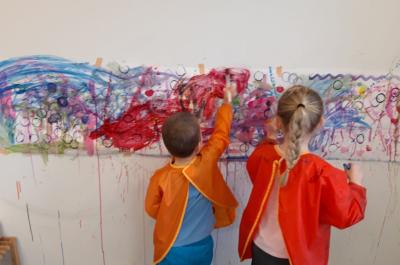 Zwei Kinder malen an eine Wand.