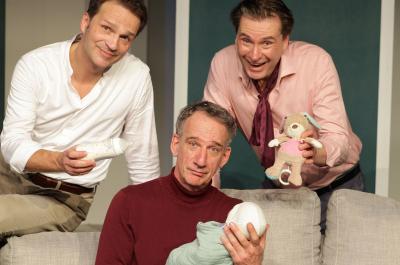 Ein Szenenbild des Stückes Drei Männer und ein Baby. Darauf zu sehen sind drei Männer, einer von ihnen hält ein Baby.